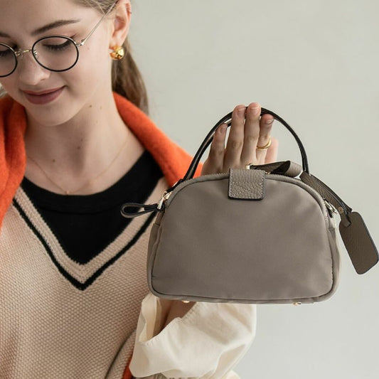 A female model is holding a tote bag "Baby Nylon Loche". Color: Greige (Gold-color hardware)