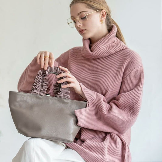 A female model is holding a hand bag "Frillka". Color:Gray x Ash pink