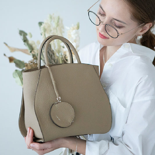 A female model is holding a tote bag "Crymit mini". Color:Greige