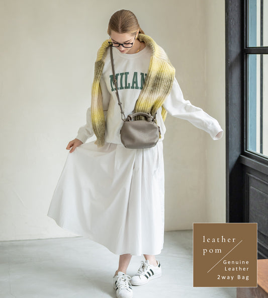 A female model is carrying a shoulder bag "Leatherpom S" over her shoulder. Color:Gray