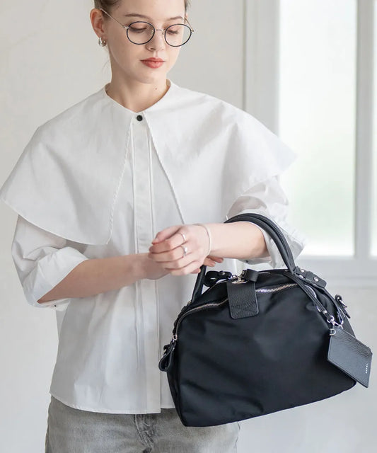 A female model is holding a hand bag "Mini Nylon Loche".Color:Black