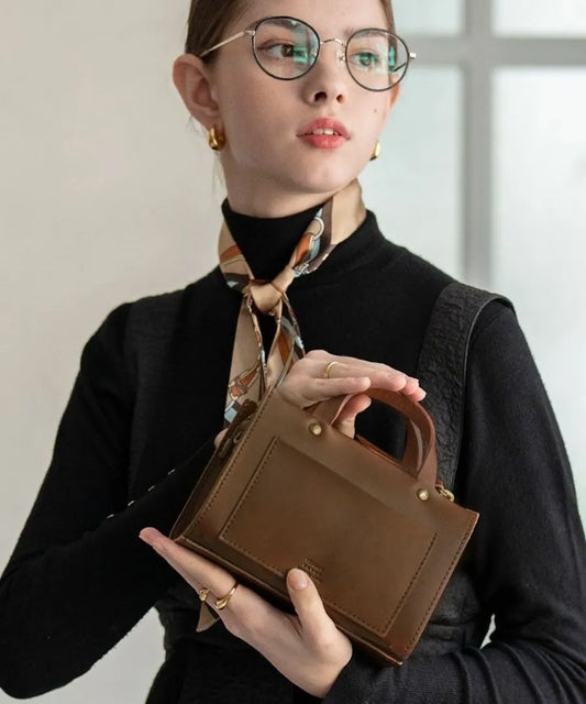 A female model is holding a hand bag "Porle". Color:Brown