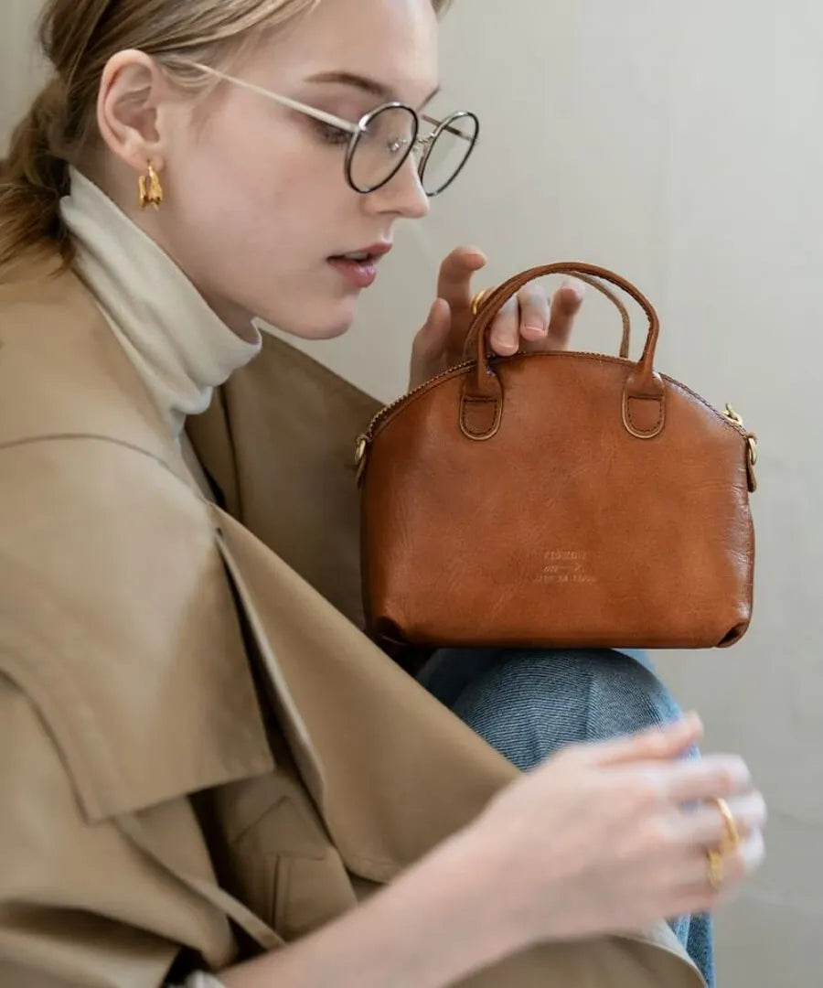 A female model is holding a bag "Light leather boston mini" Color:Camel