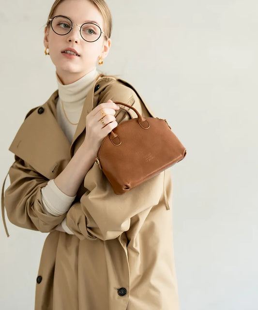 A female model is holding a bag "Light leather boston mini" Color:Camel