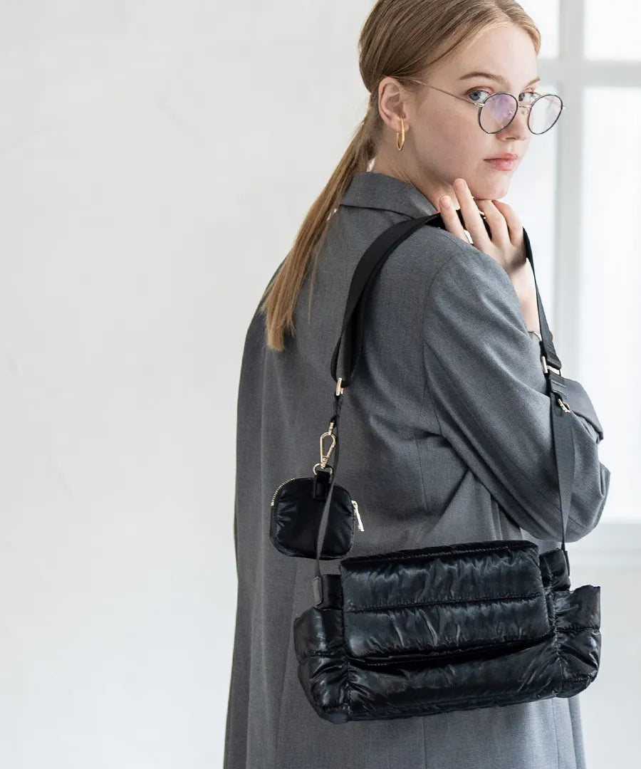 A female model is carrying a shoulder bag "Flaum" over her shoulder.