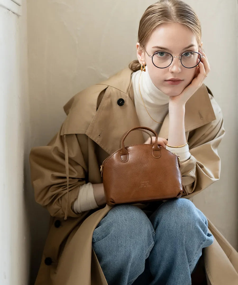 A female model is holding a bag "Light leather boston mini" Color:Camel