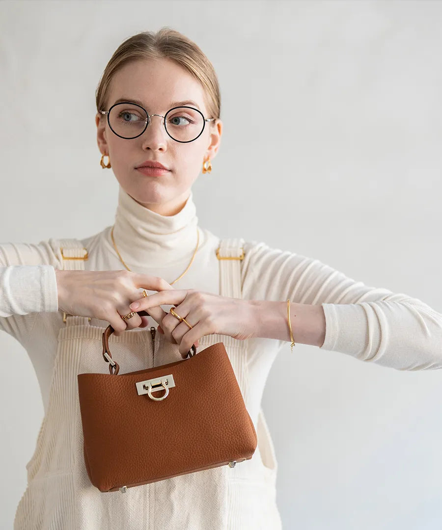 A female model is holding a tote bag "Baby Marollet". Color: Camel