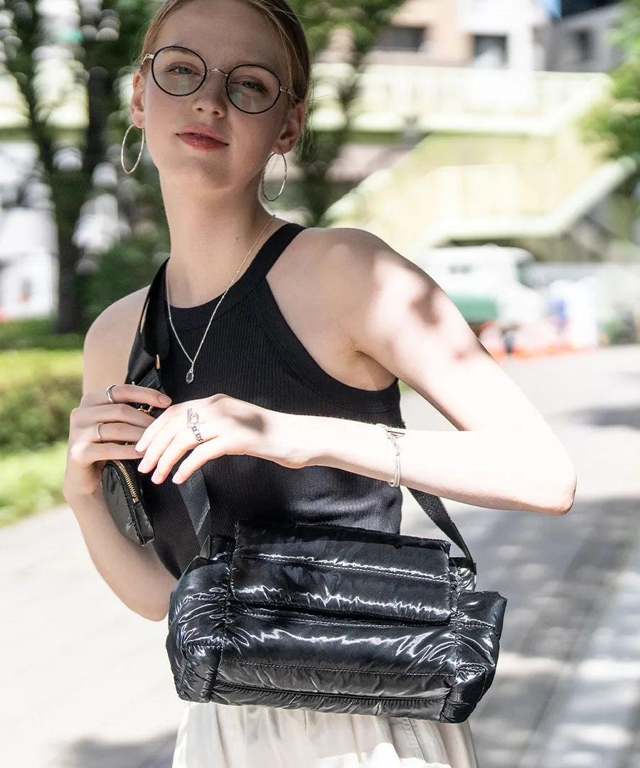 A female model is carrying a shoulder bag "Flaum" over her shoulder.