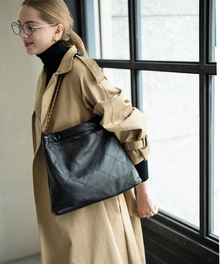 A female model is carrying a shoulder bag "barmed" over her shoulder.