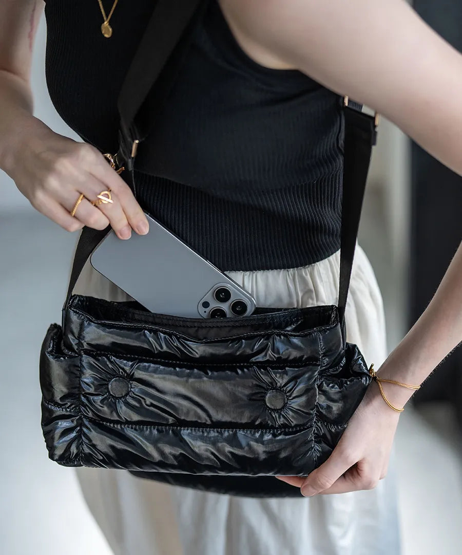 A female model is carrying a shoulder bag "Flaum" over her shoulder.