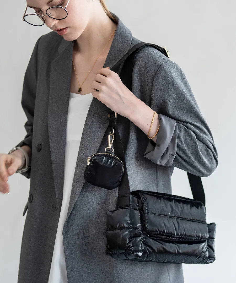 A female model is carrying a shoulder bag "Flaum" over her shoulder.