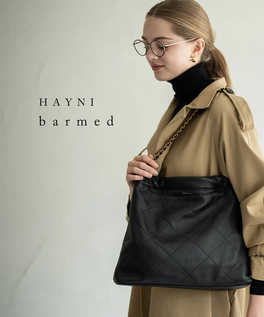 A female model is carrying a shoulder bag "Barmed" over her shoulder. Color:Black