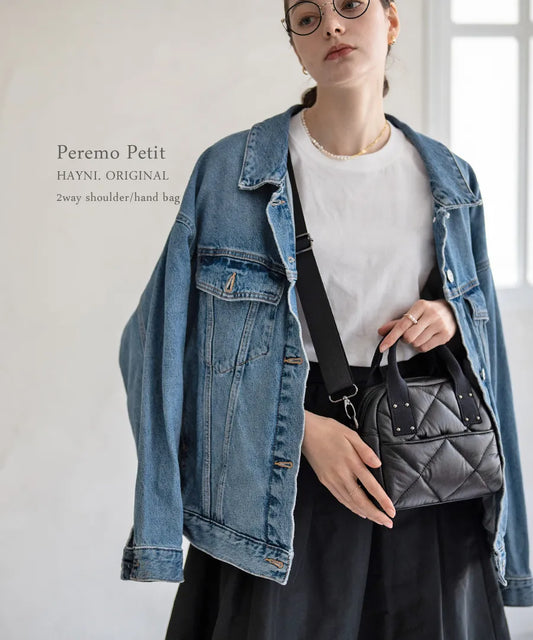 A female model is carrying a body bag "peremopetit" over her shoulder.Color:Black