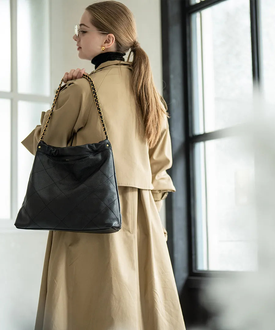 A female model is carrying a shoulder bag "barmed" over her shoulder.