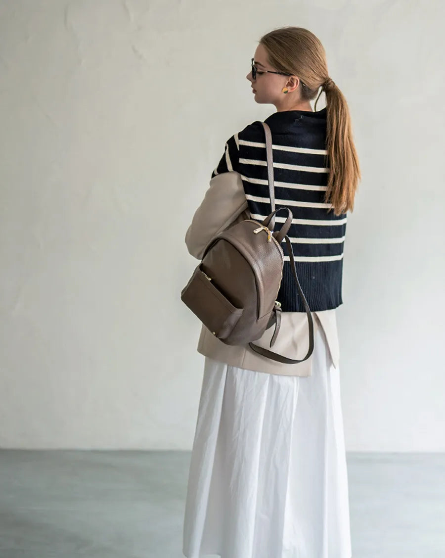 A female model is carrying a backpack "Arioso". Color:Taupe