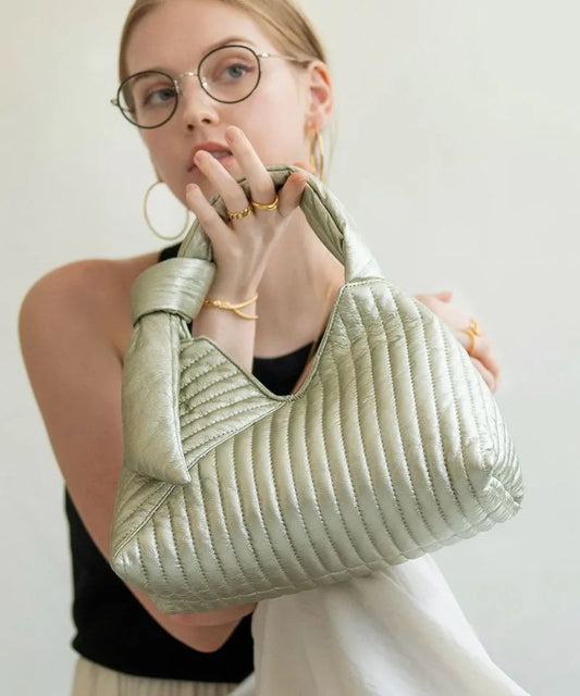 A female model is holding a hand bag "Aulie" Color:Champagne silver