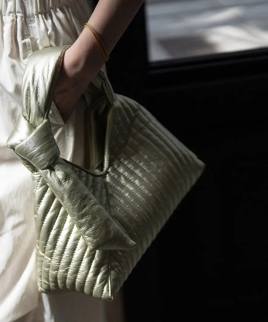 A female model is holding a hand bag "Aulie" Color:Champagne silver