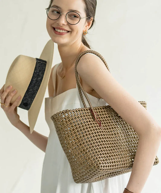 The female model is carrying a basket bag 「Basq(Color:Bronze)」over her shoulder