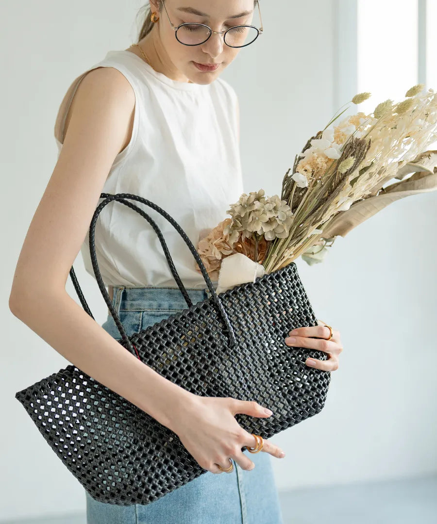 The female model is holding a basket bag「Basq」Color: Black