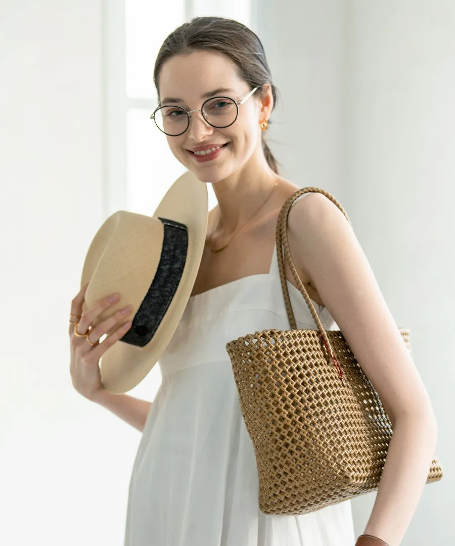 The female model is carrying a basket bag 「Basq(Color:Bronze)」over her shoulder