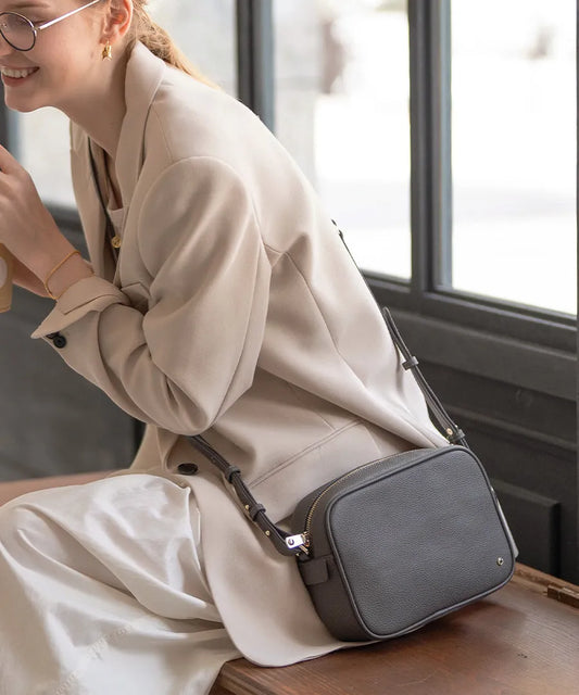 A female model is sitting with a shoulder bag "Conwy" slung across her shoulder. Color:Dark gray