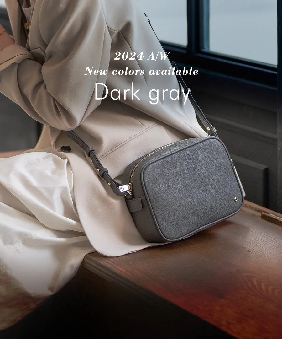 A female model is sitting with a shoulder bag "Conwy" slung across her shoulder. Color:Dark gray