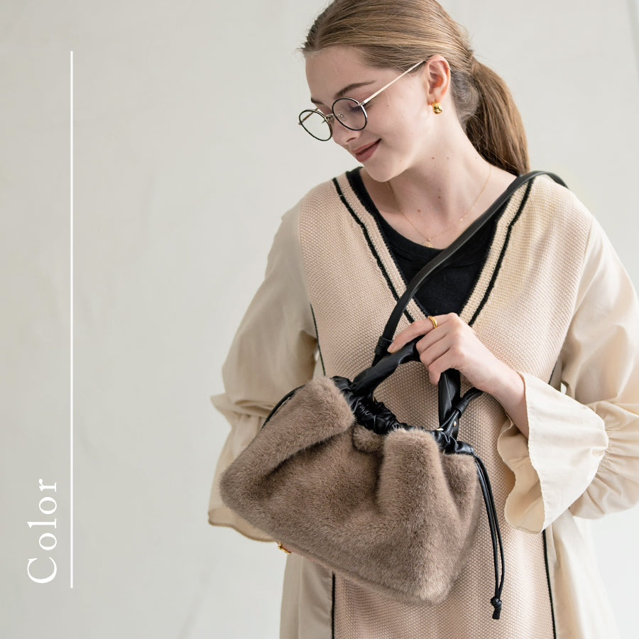 A female model is carrying a shoulder bag "Dollfur" over her shoulder. Color: Mocha greige