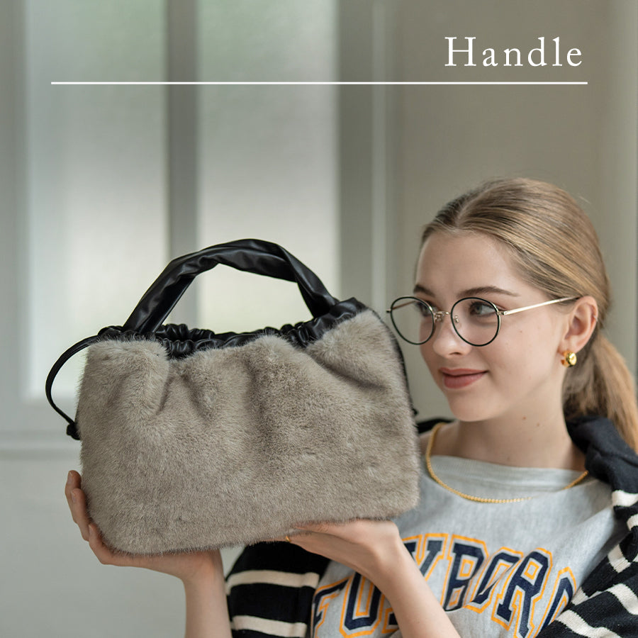 A female model is holding a tote bag "Dollfur". Color: Light gray