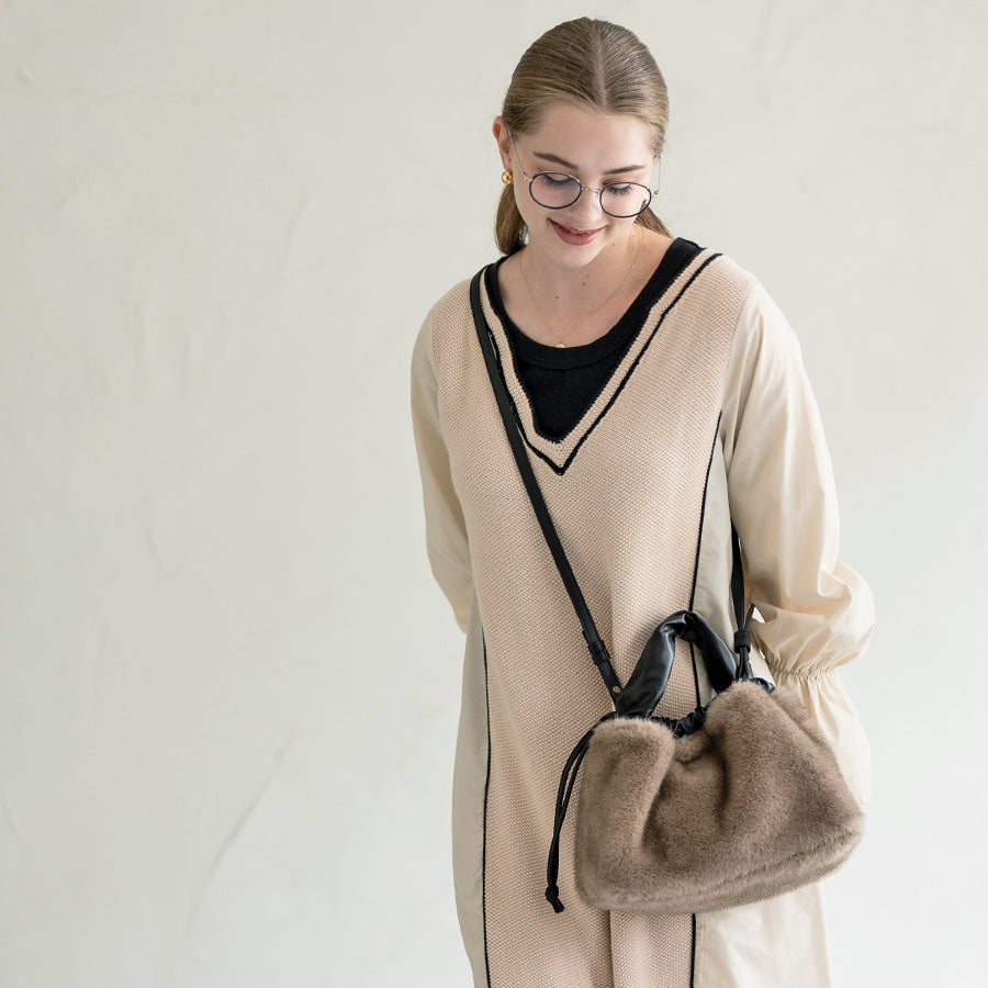 A female model is carrying a shoulder bag "Dollfur" over her shoulder. Color: Mocha greige