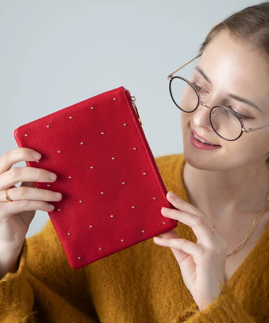 A female model is holding a leather pouch "Dotlpouch M" Color:Cherry red (gold dot)