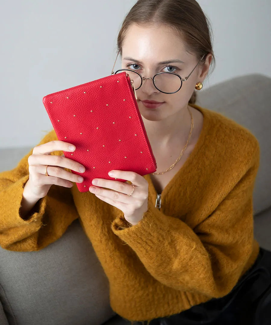 A female model is holding a leather pouch "Dotlpouch M" Color:Cherry red (gold dot)