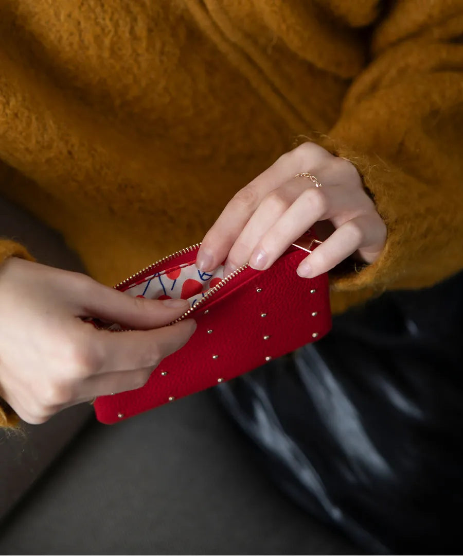 A female model is holding a leather pouch "Dotlpouch M" Color:Cherry red (gold dot)