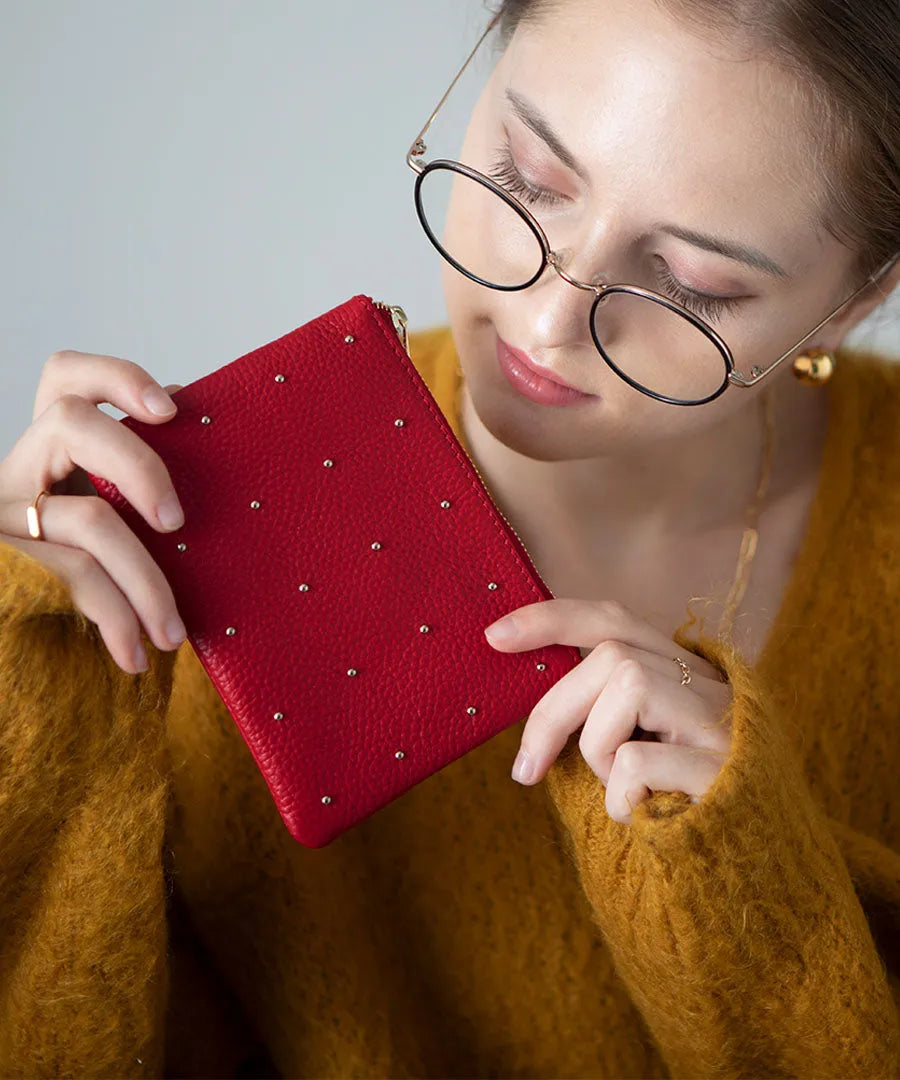 A female model is holding a leather pouch "Dotlpouch S" Color:Cherry red (gold dot)