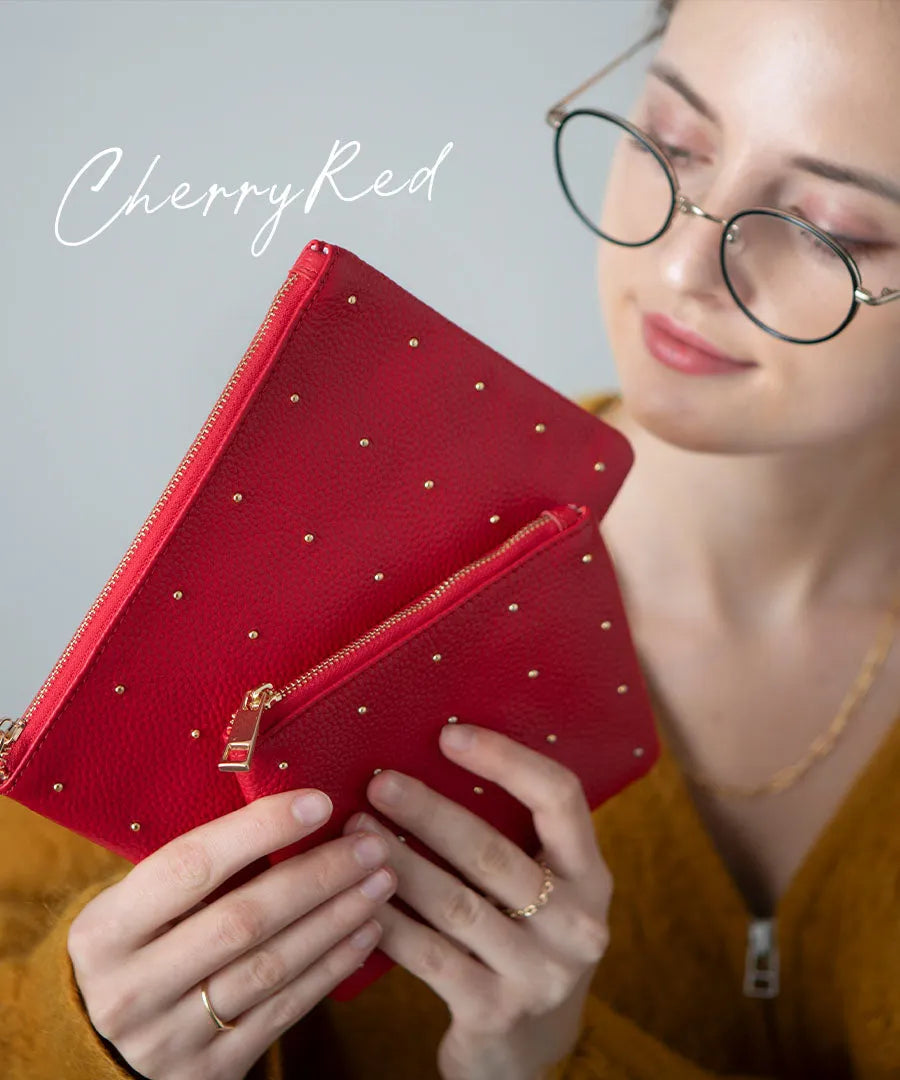 A female model is holding a leather pouch "Dotlpouch S" Color:Cherry red (gold dot)