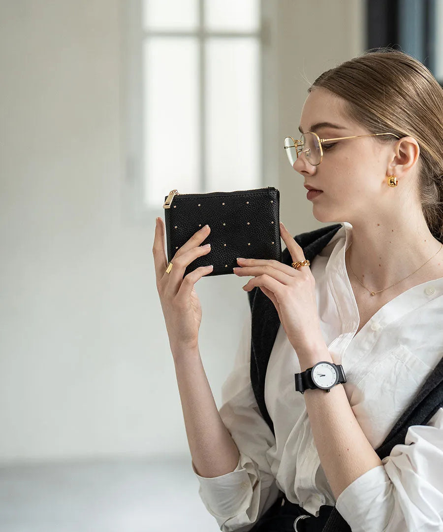 A female model is holding a leather pouch "Dotlpouch S" Color:Gold dot