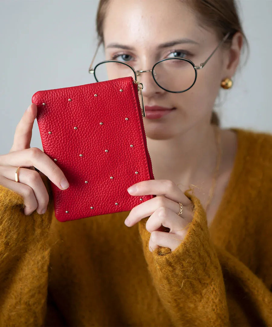 A female model is holding a leather pouch "Dotlpouch S" Color:Cherry red (gold dot)