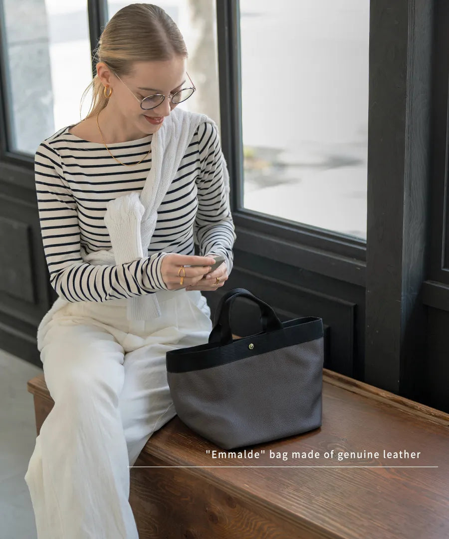 Colors of the seated female model and tote bag "Emalde": dark gray x black.