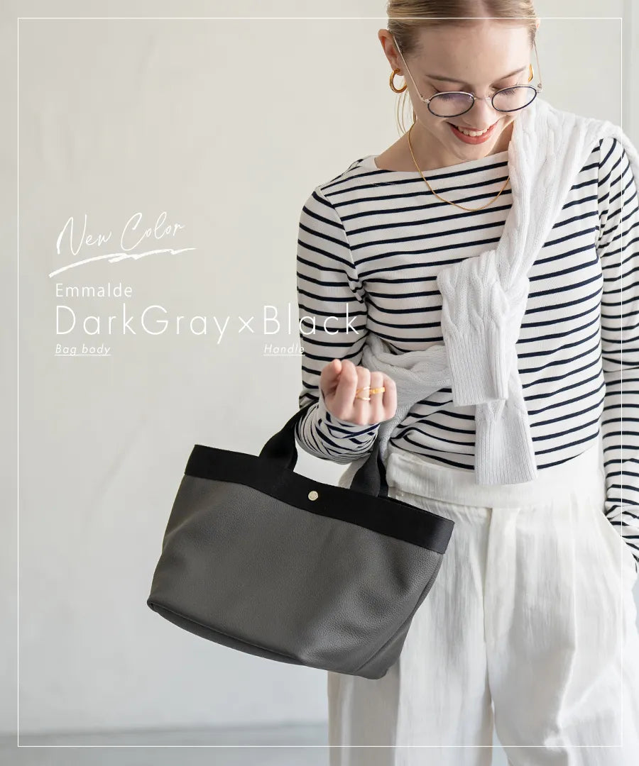 A female model is holding a tote bag "Emmalde" in colors: dark gray x black.