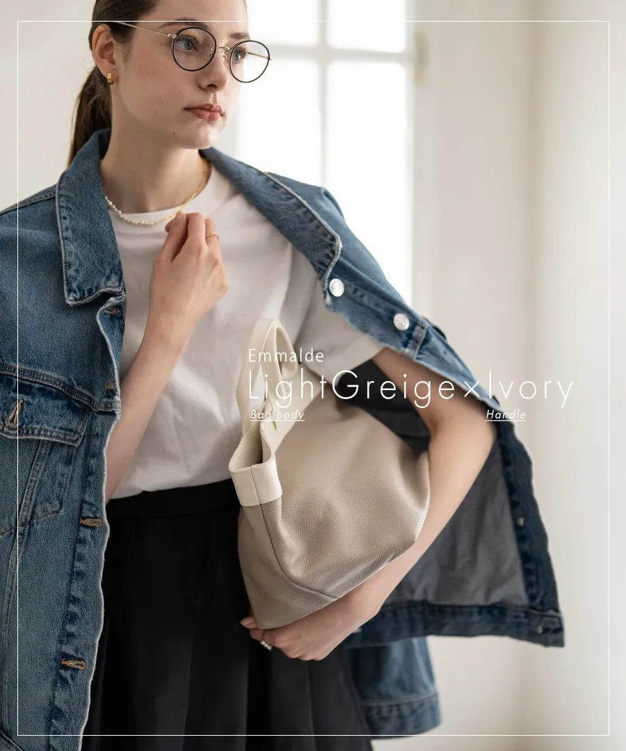 A female model is holding a tote bag "Emmalde" in colors: light gray x ivory.