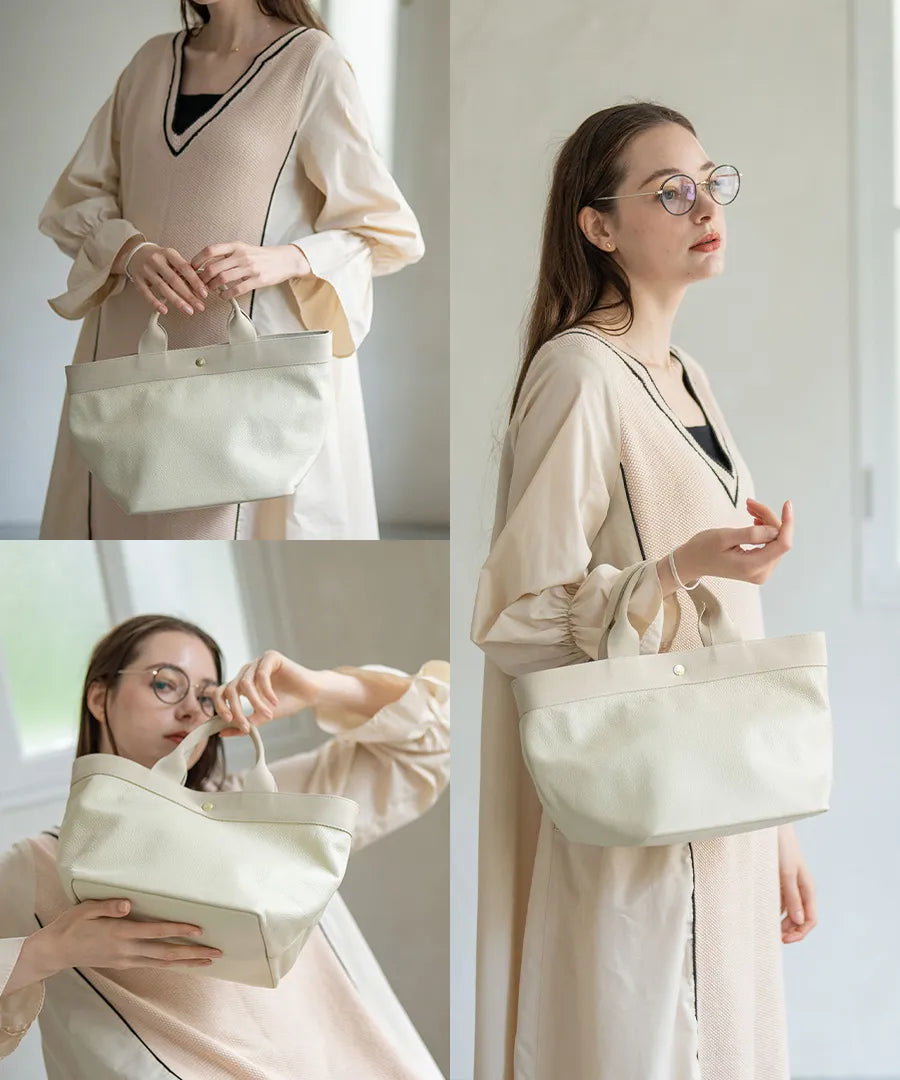 A female model is holding a tote bag "Emmalde" in colors: Ivory x Light gray.