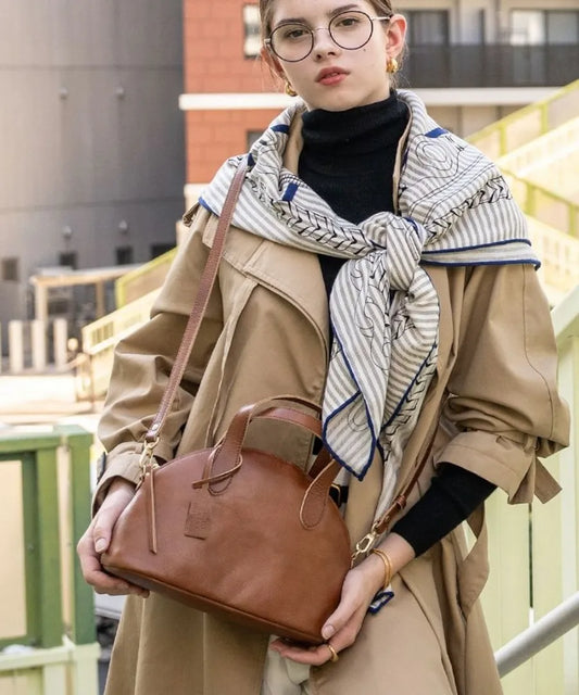 A female model is carrying a shoulder bag "Ervi" over her shoulder. Color: Camel