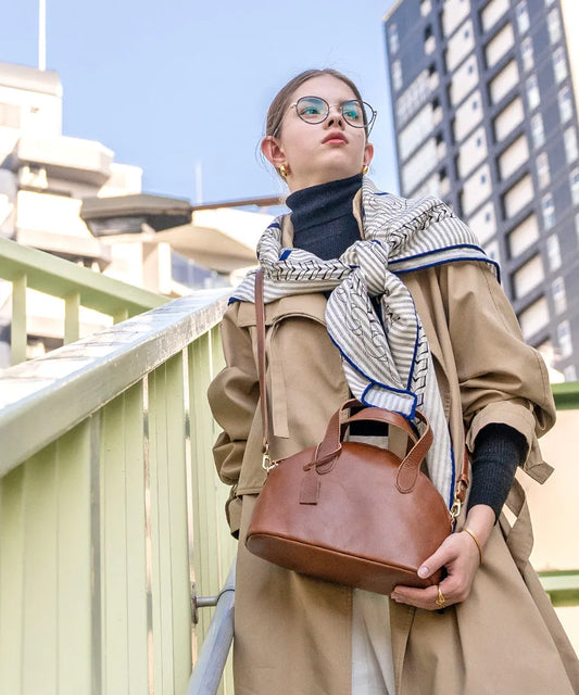 A female model is carrying a shoulder bag "Ervi" over her shoulder. Color: Camel