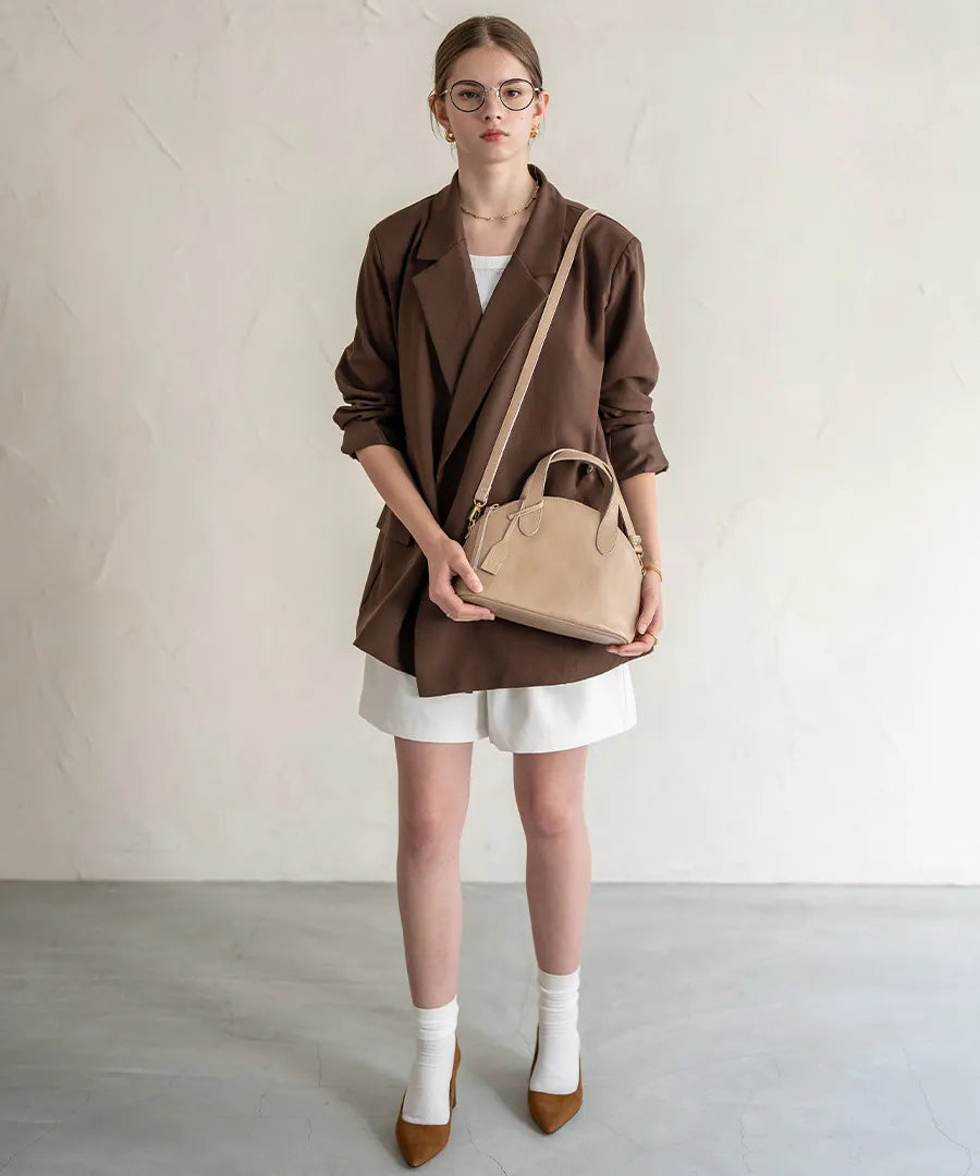 A female model is carrying a shoulder bag "Ervi" over her shoulder. Color: Sand greige