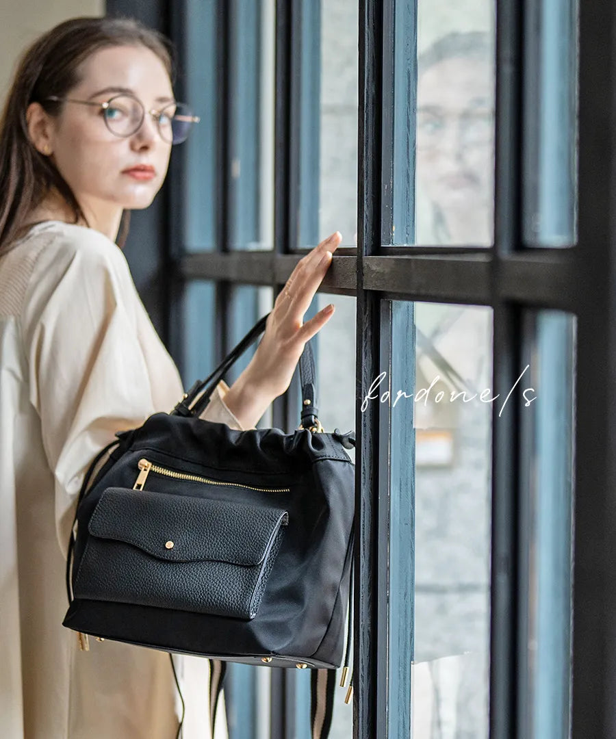 A female model is holding a shoulder bag "Fordone S".Color:Black