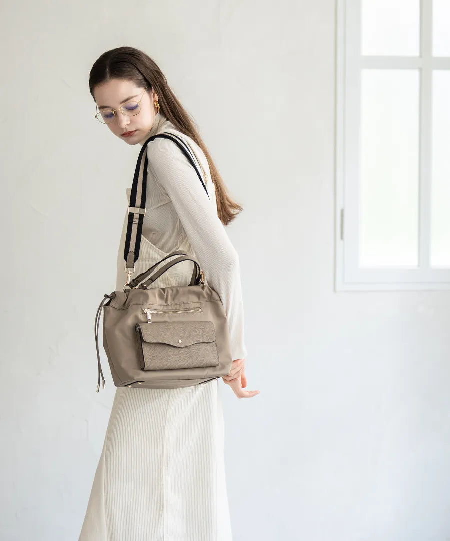 A female model is carrying a shoulder bag "Fordone S" over her shoulder.Greige