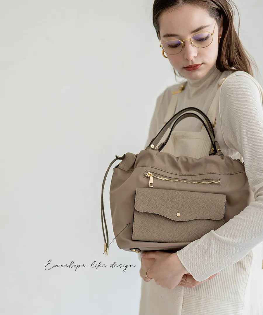 A female model is holding a shoulder bag "Fordone S".Color:Greige