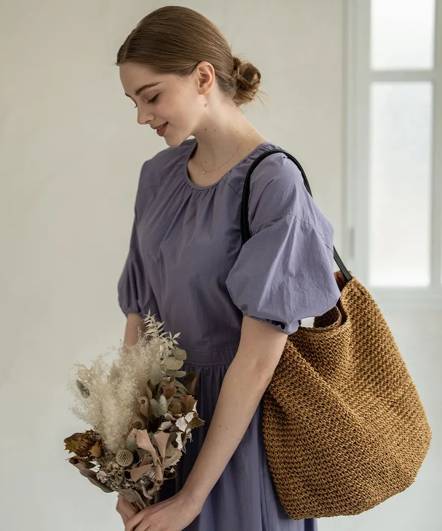 A female model is holding a tote bag "Garah".Color:Natural