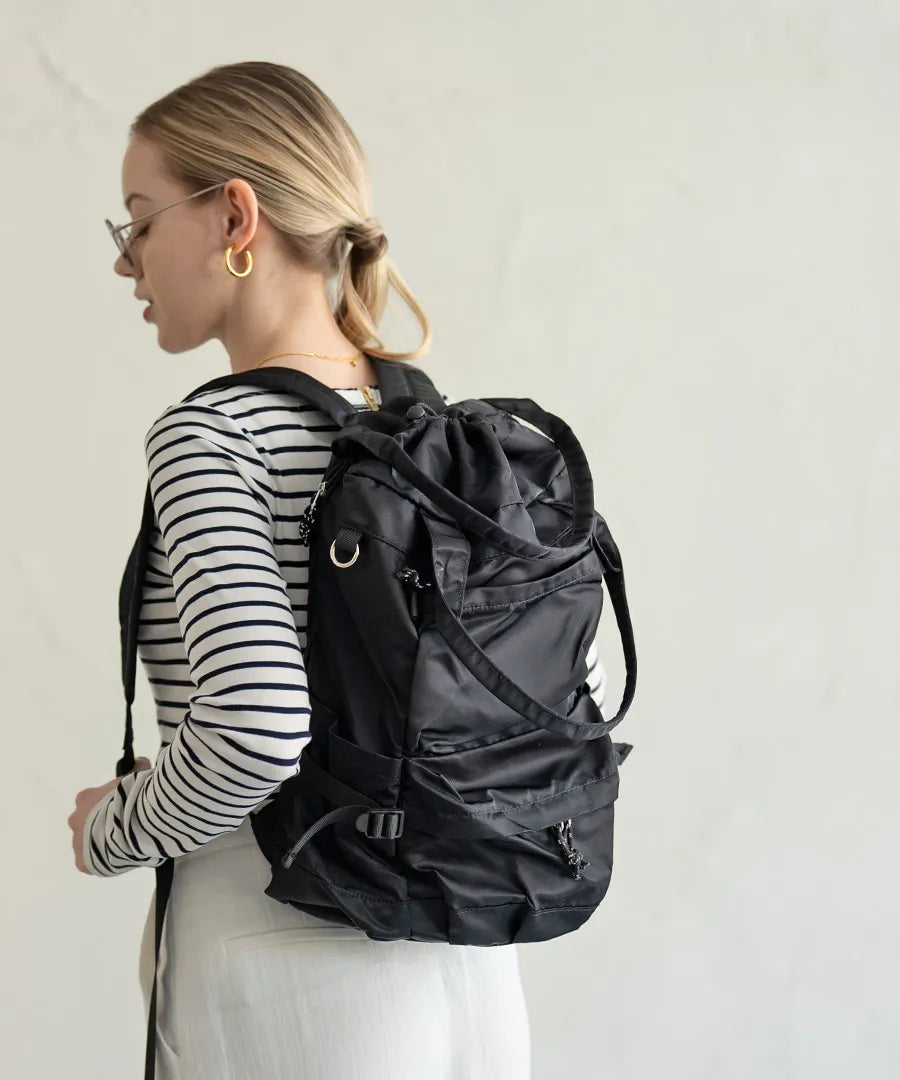 A female model is carrying a body bag "Glarca" over her shoulder.Color:Nylon black