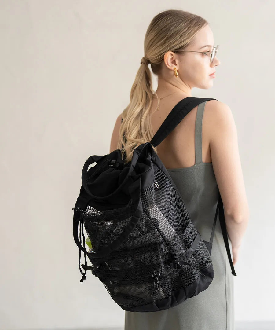 A female model is carrying a body bag "Glarca" over her shoulder.Color:Mesh black