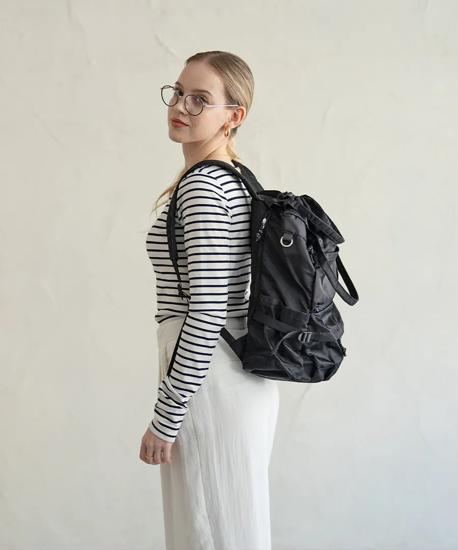 A female model is carrying a body bag "Glarca" over her shoulder.Color:Nylon black